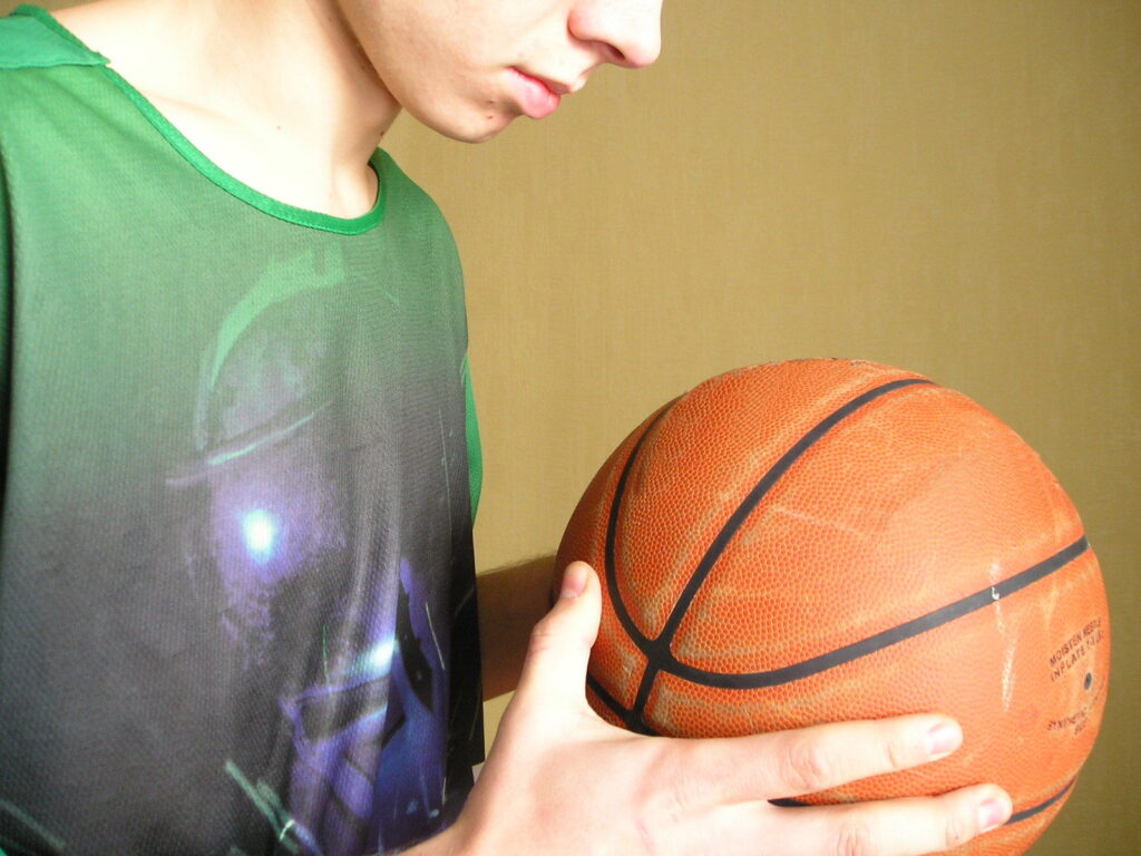 boy in green shirt looking at basketball