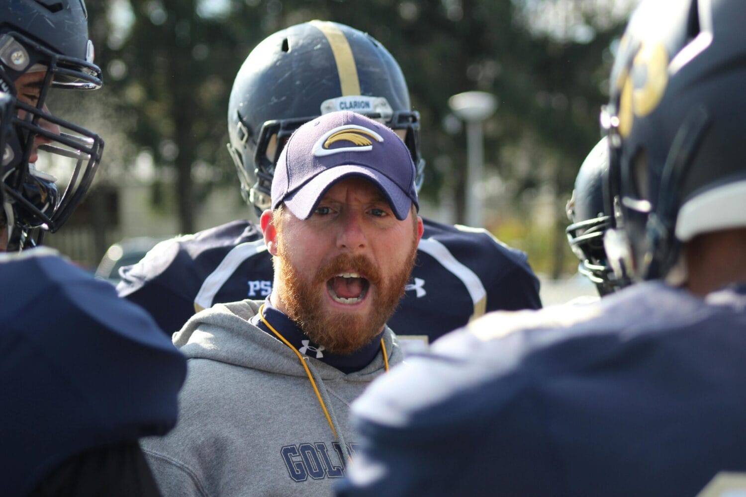 football coach motivating players in helmets