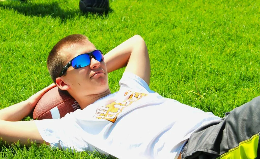 A boy and his football - Ball to Life Sports boy laying with head propped on football