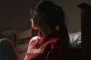 young lady sitting on floor looking out the window
