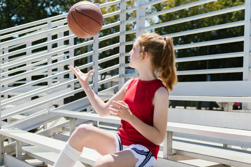 girl sitting in bleachers with basketball